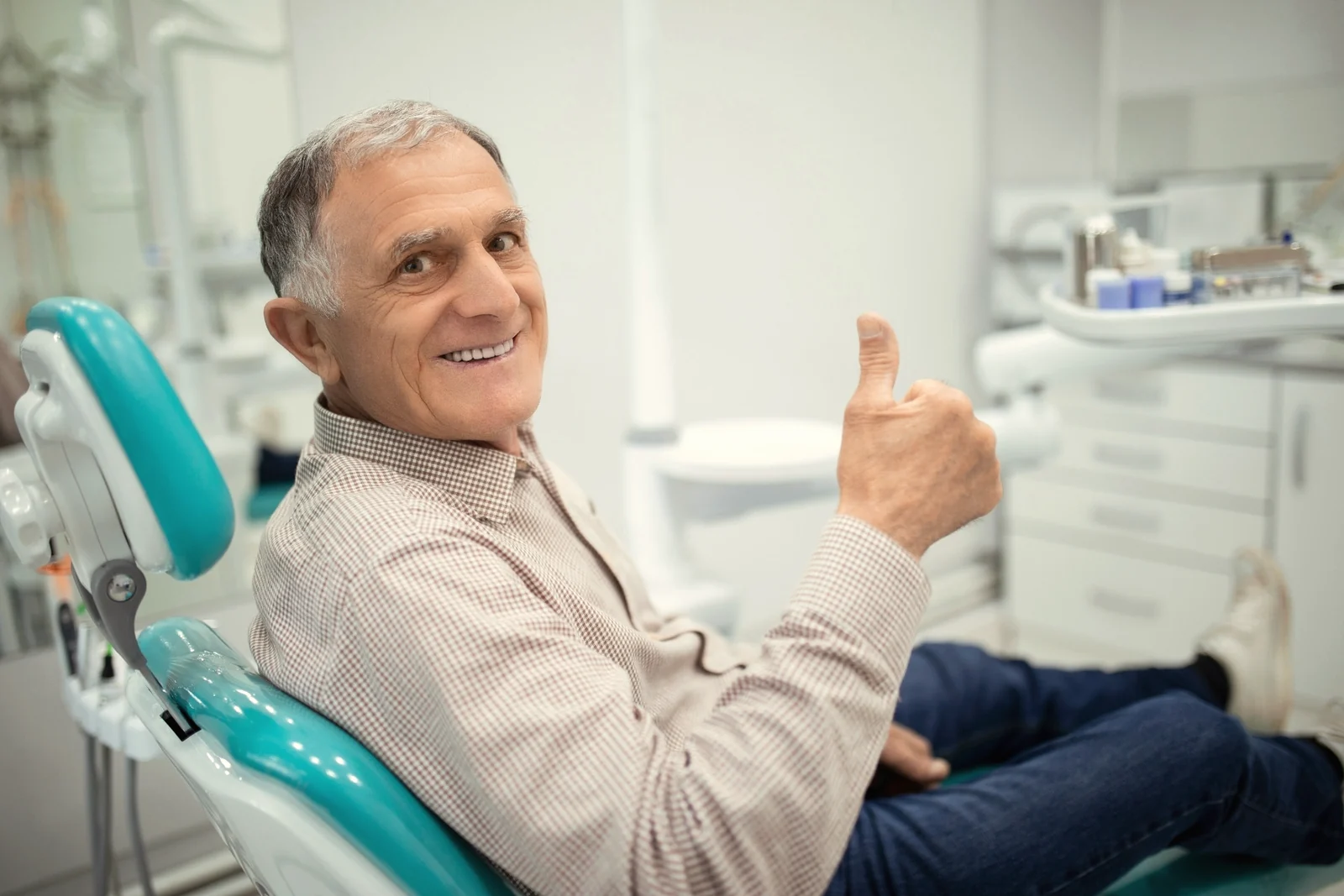 Paciente mayor sonriente sentado en el sillón dental antes de una revisión de encías