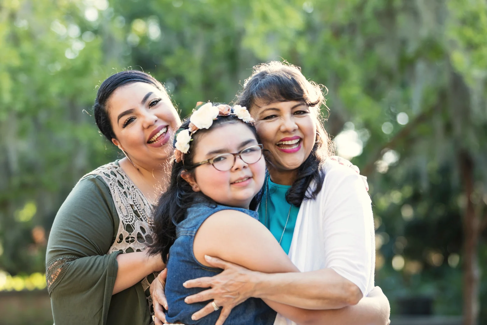 Familia latina de tres generaciones abrazada y sonriendo