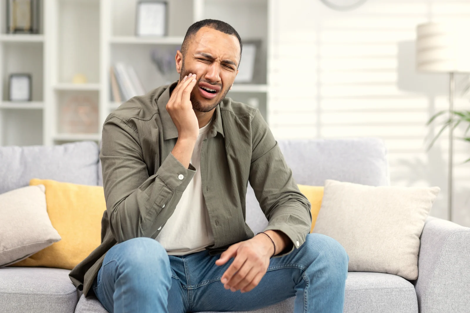 Hombre en el sofá de casa con dolor de muela