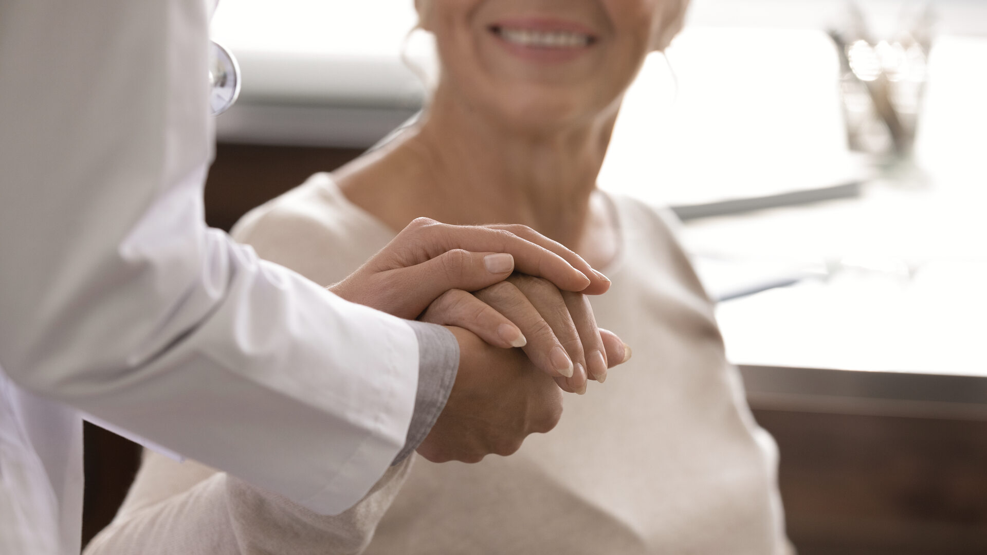 Dentista tomando con calma la mano de una paciente mayor durante la consulta