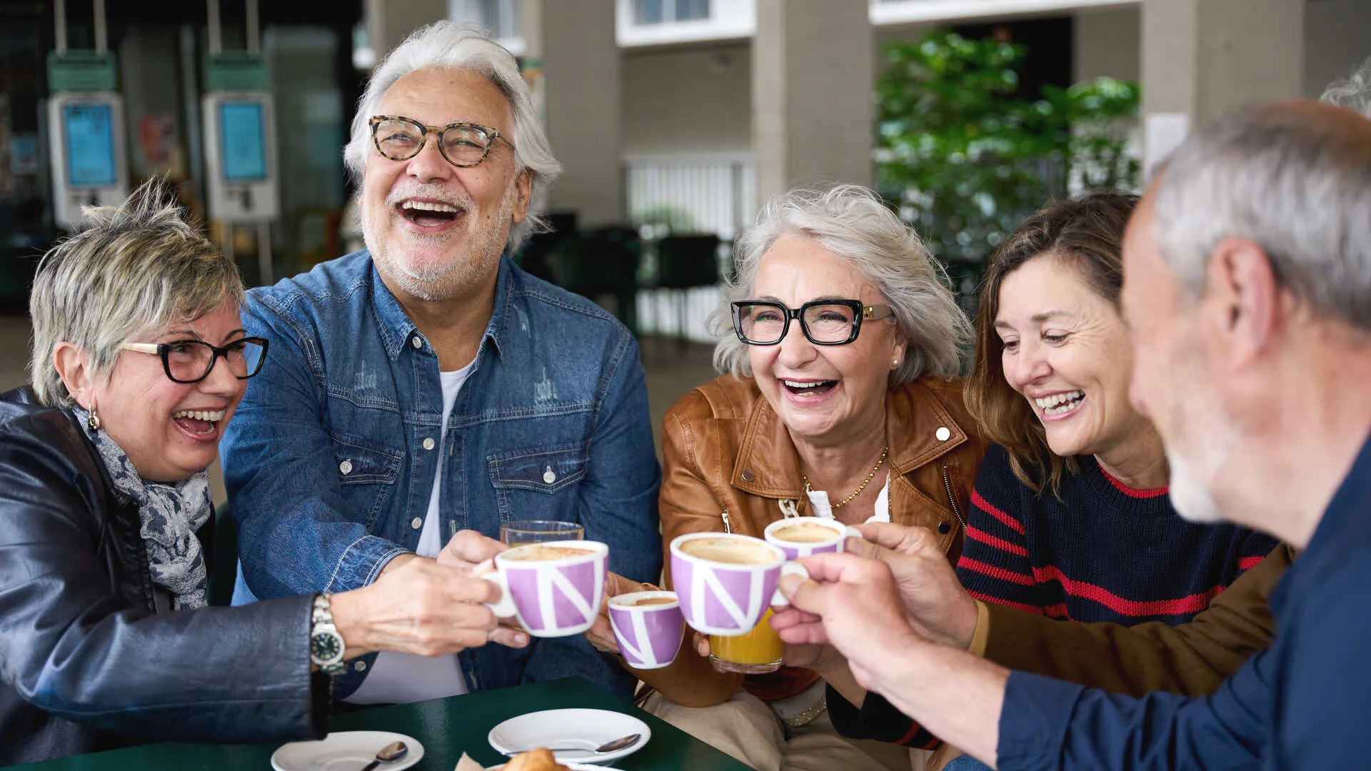 Grupo de adultos mayores conversando y riendo alrededor de un café