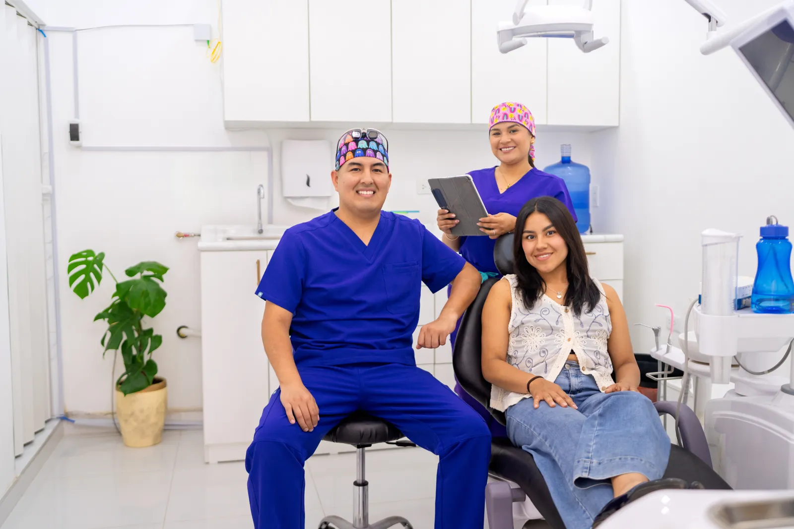 Dentista y asistente junto a una paciente en el consultorio dental