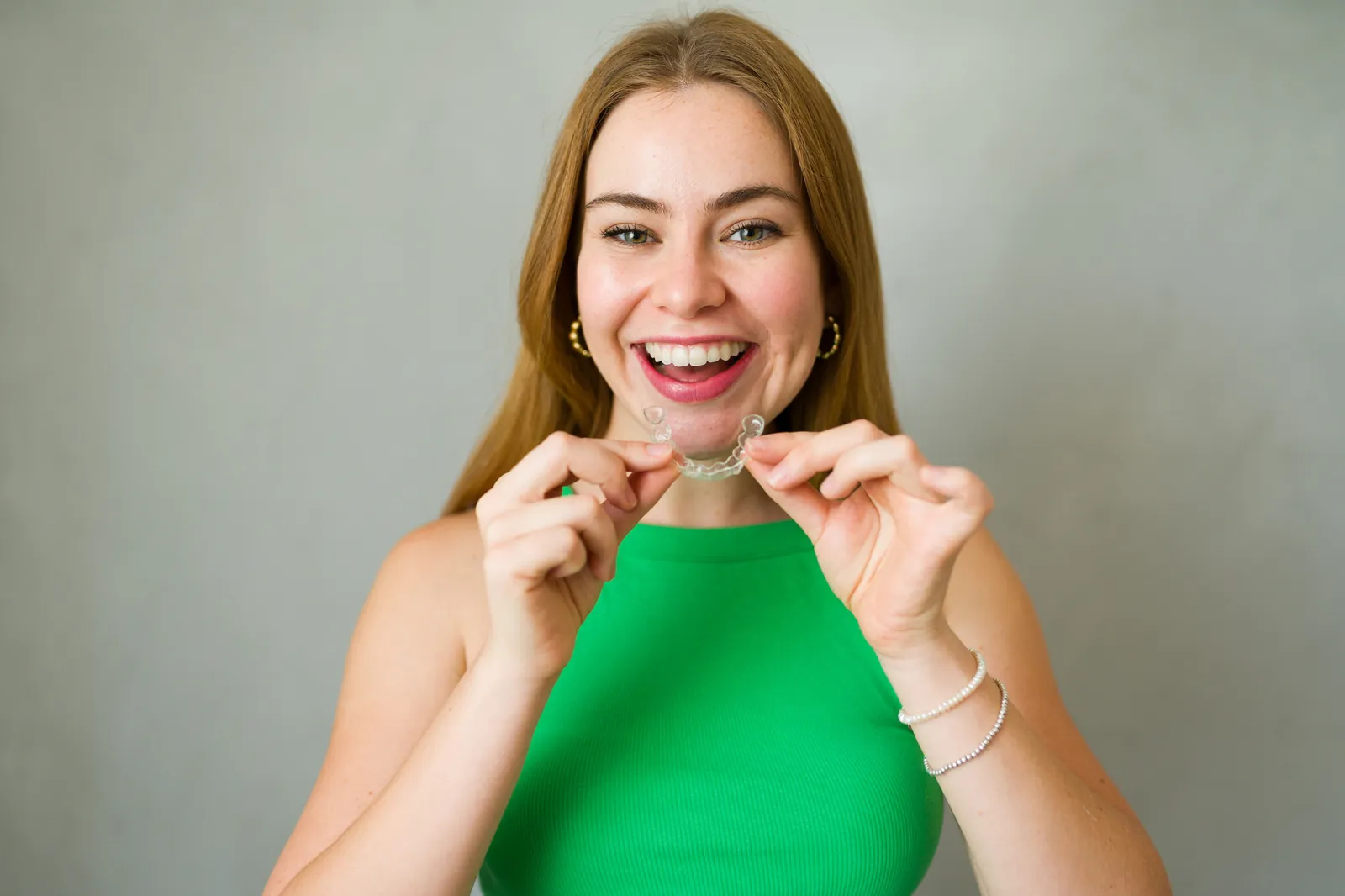 Smiling woman putting in a clear dental retainer