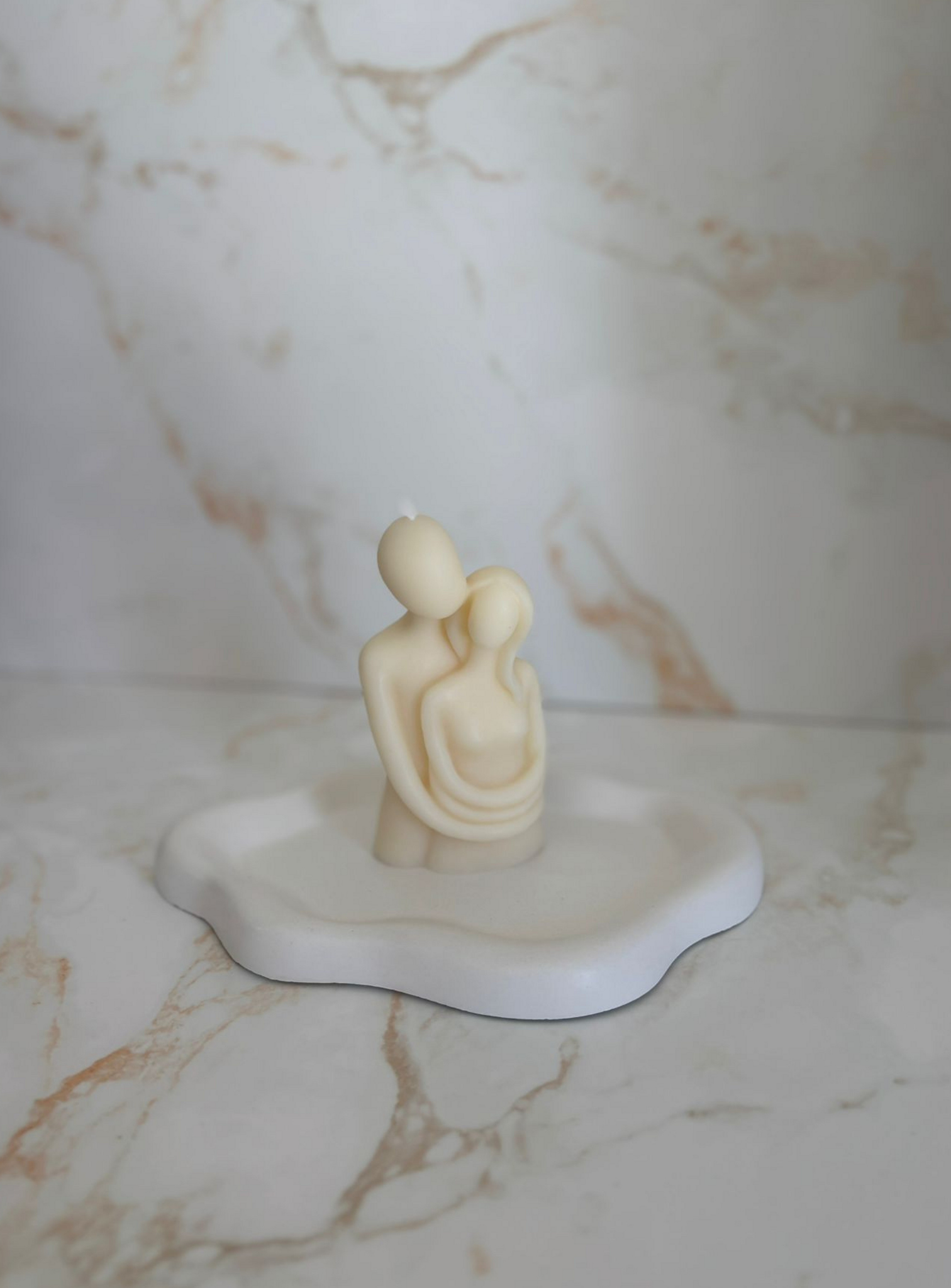 Candle representing a romantig hug between two two lovers, over a plate