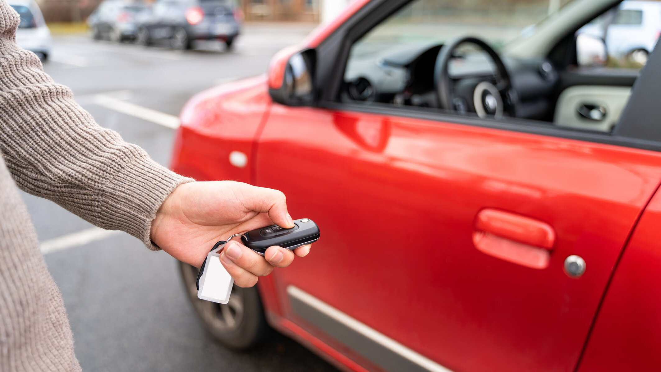 Hand hält Autoschlüssel vor rotem Auto nach Verkehrsunfall – Nutzungsausfallentschädigung