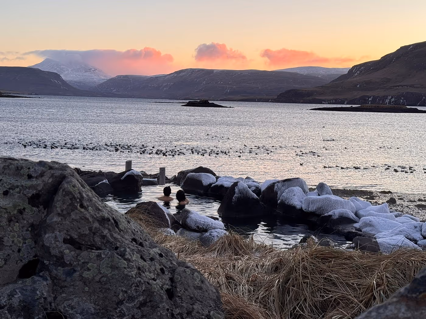 People swimming in Hvammsvik hot springs in Hvammsvík, Iceland