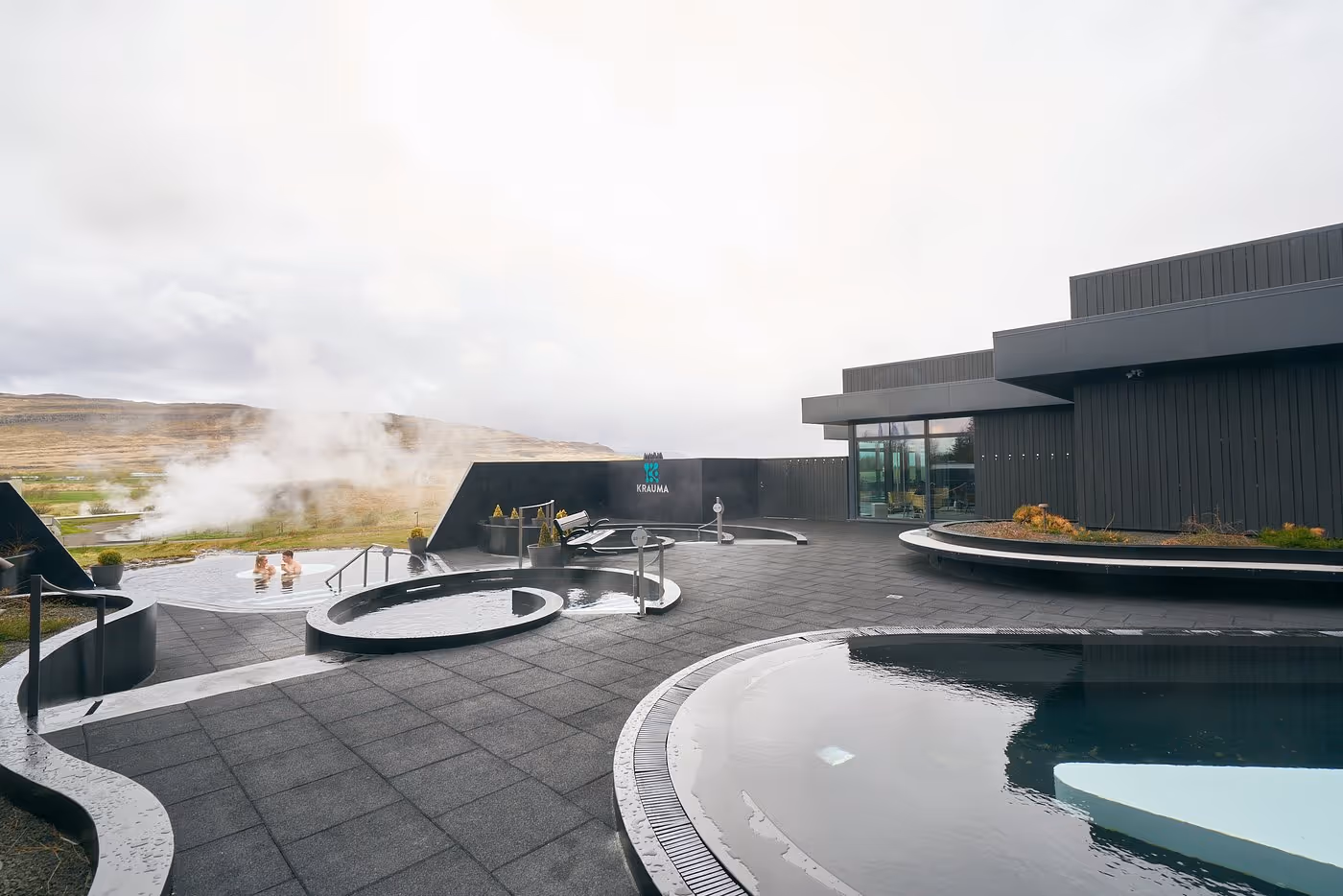 people swimming in krauma geothermal baths near Reykholt, Iceland