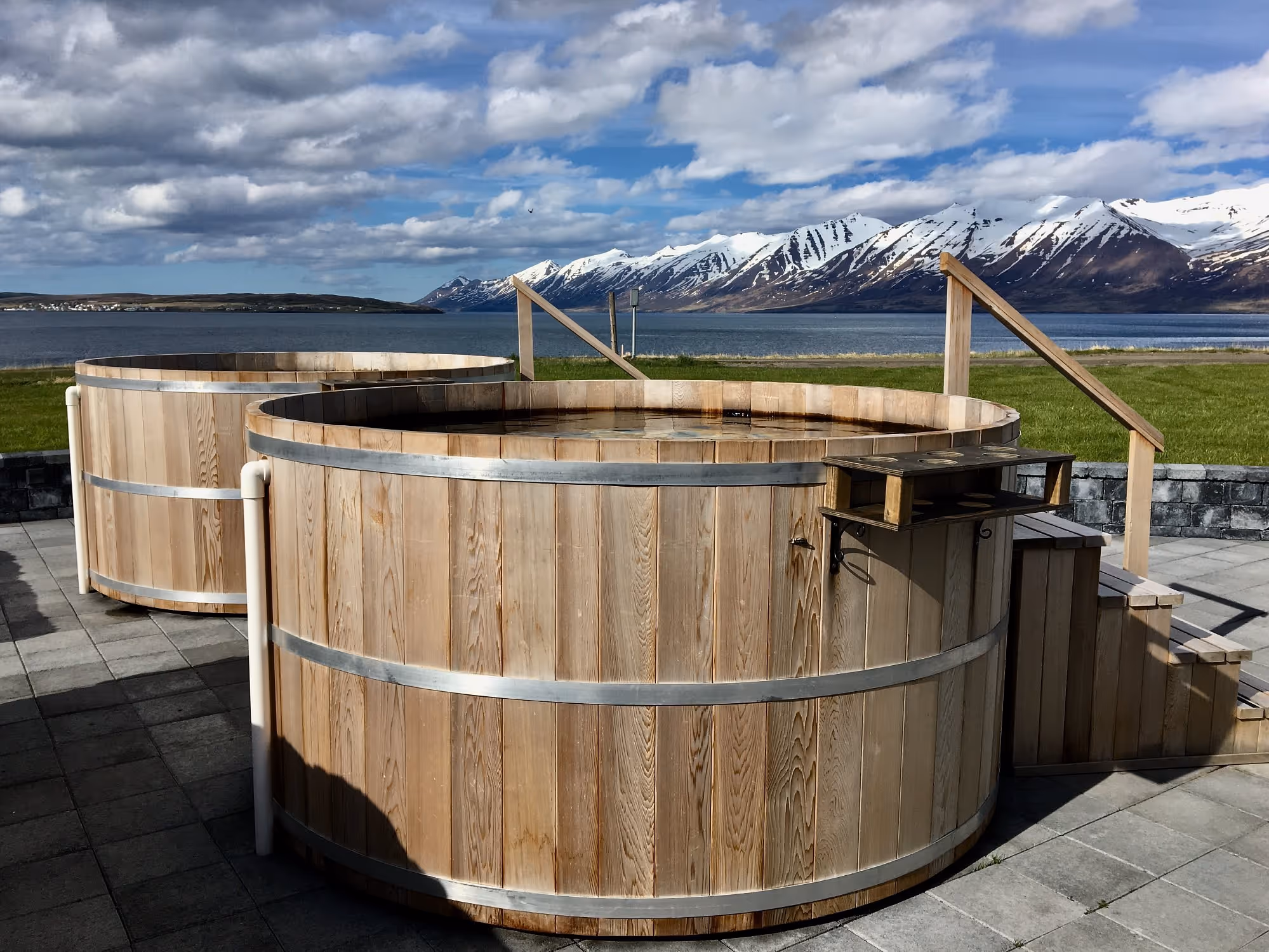 outdoor hot tubs near a bay and mountains in the background in Bjorbodin Beer Spa, near Dalvik, Iceland