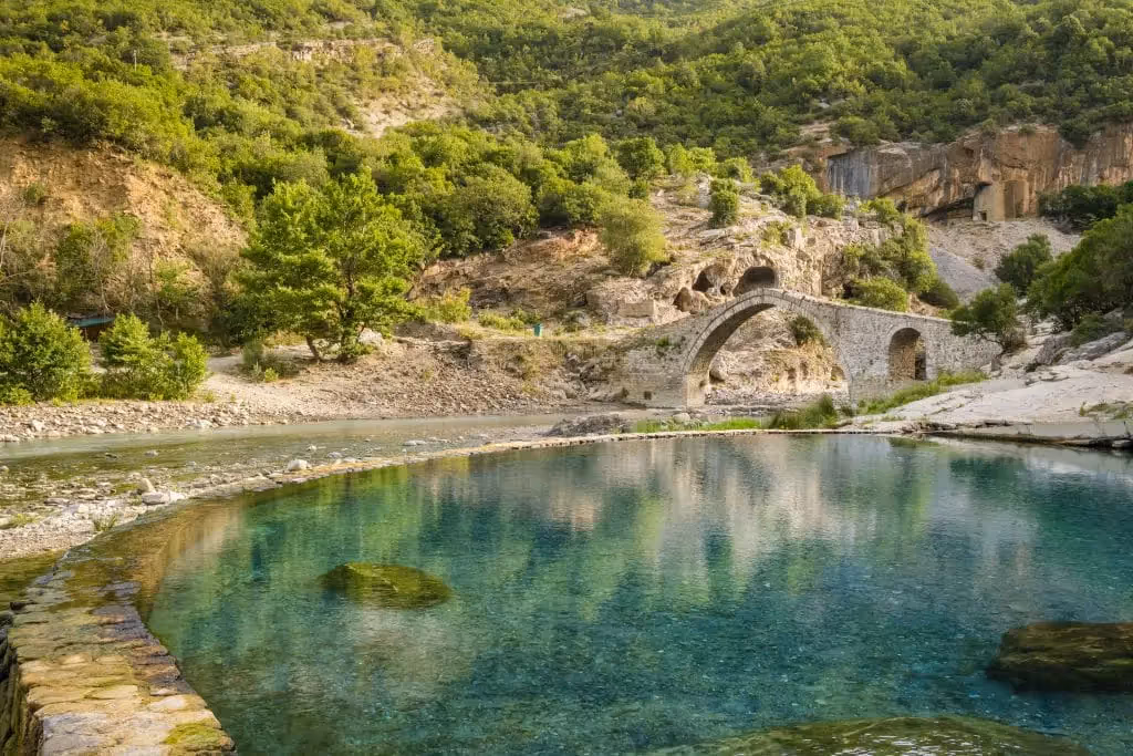 Natural hot springs with bridge in the background in Elbasan Thermal Springs