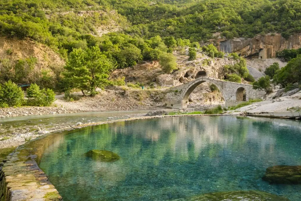 Natural hot springs with bridge in the background in Elbasan Thermal Springs