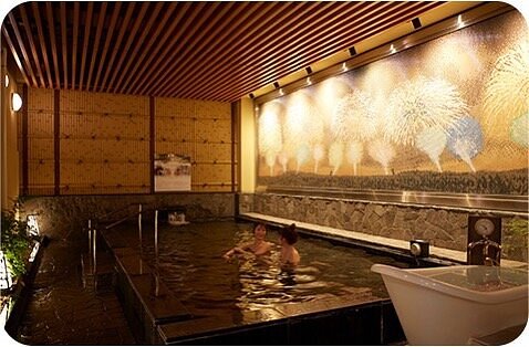 People soaking in dim light onsen Thermae-Yu, Japan