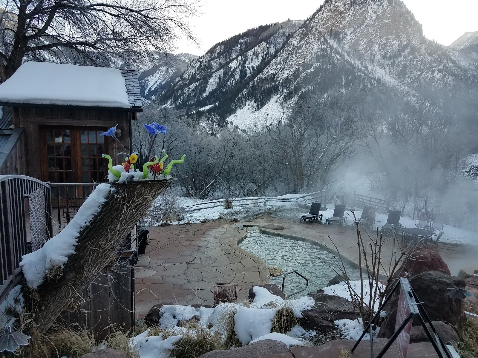 Snow-covered outdoor hot spring pool surrounded by winter landscape and mountains at Avalanche Ranch Cabins & Hot Springs, Colorado.