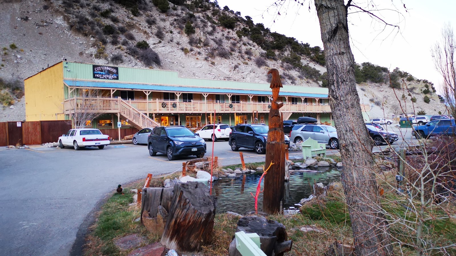 Exterior view of Cottonwood Hot Springs Inn & Spa, showing motel-style building with parked cars and a landscaped pond in Buena Vista, Colorado.