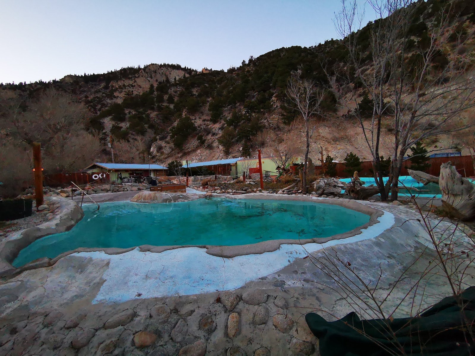 Outdoor spa pool filled with clear blue water at Cottonwood Hot Springs Inn & Spa in Buena Vista, Colorado, surrounded by trees and hills.