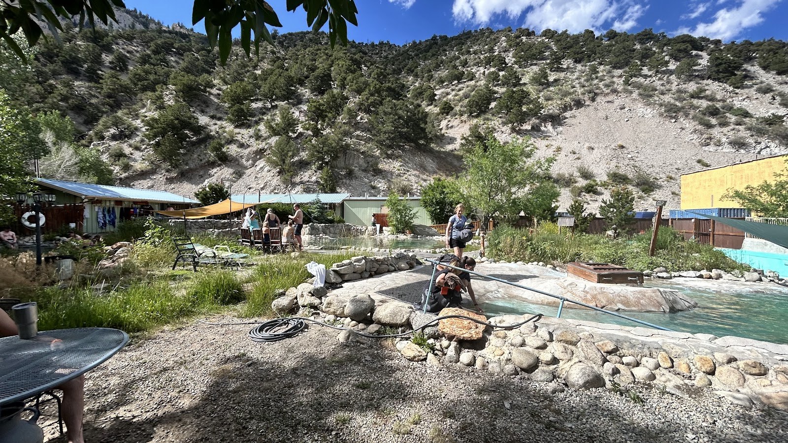 Visitors enjoying sunny day at the outdoor spa pools of Cottonwood Hot Springs Inn & Spa with mountainous backdrop near Buena Vista, Colorado.