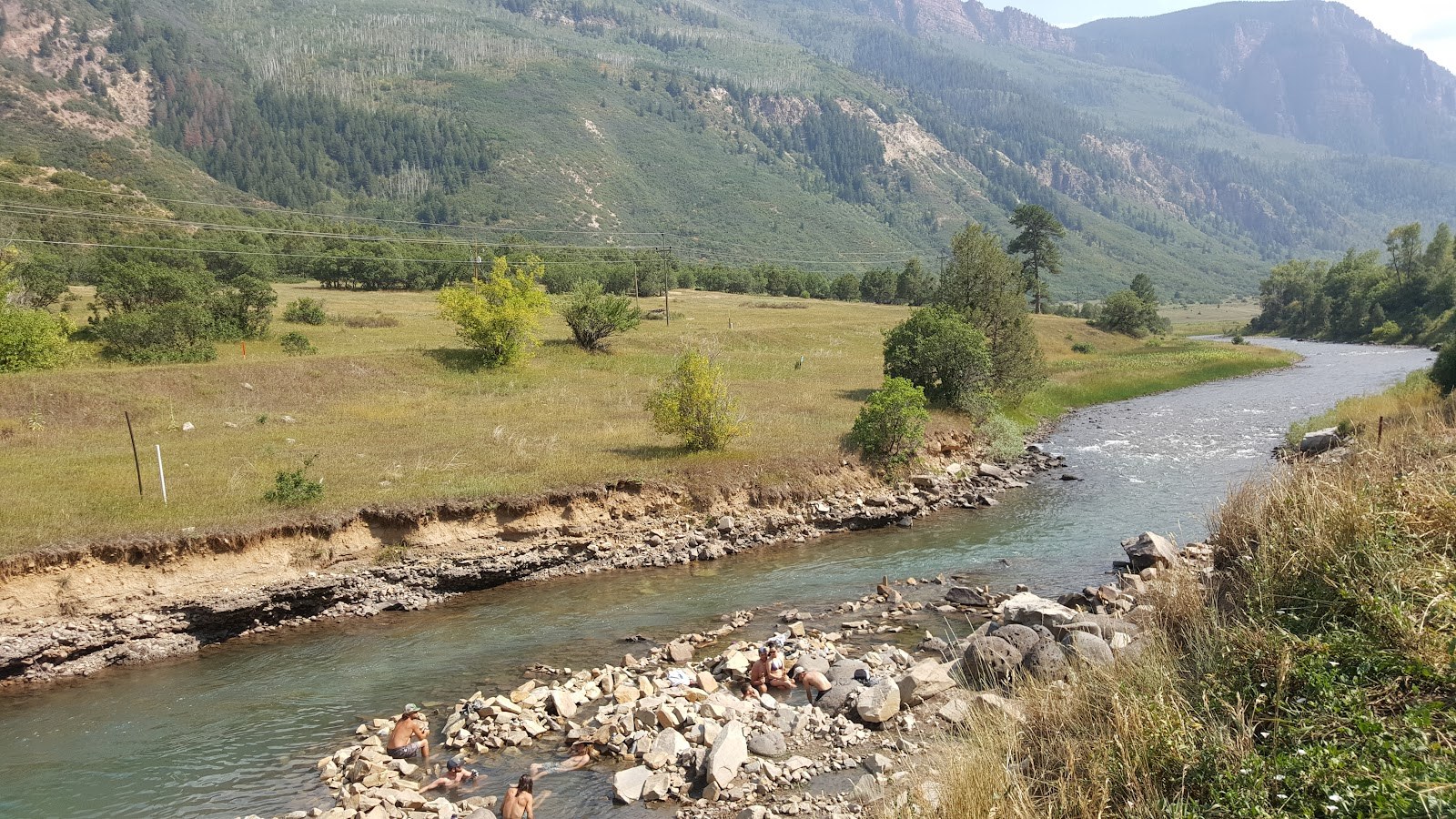 People soaking and relaxing in natural hot spring pools by the river at Penny Hot Springs near Redstone, Colorado, United States.