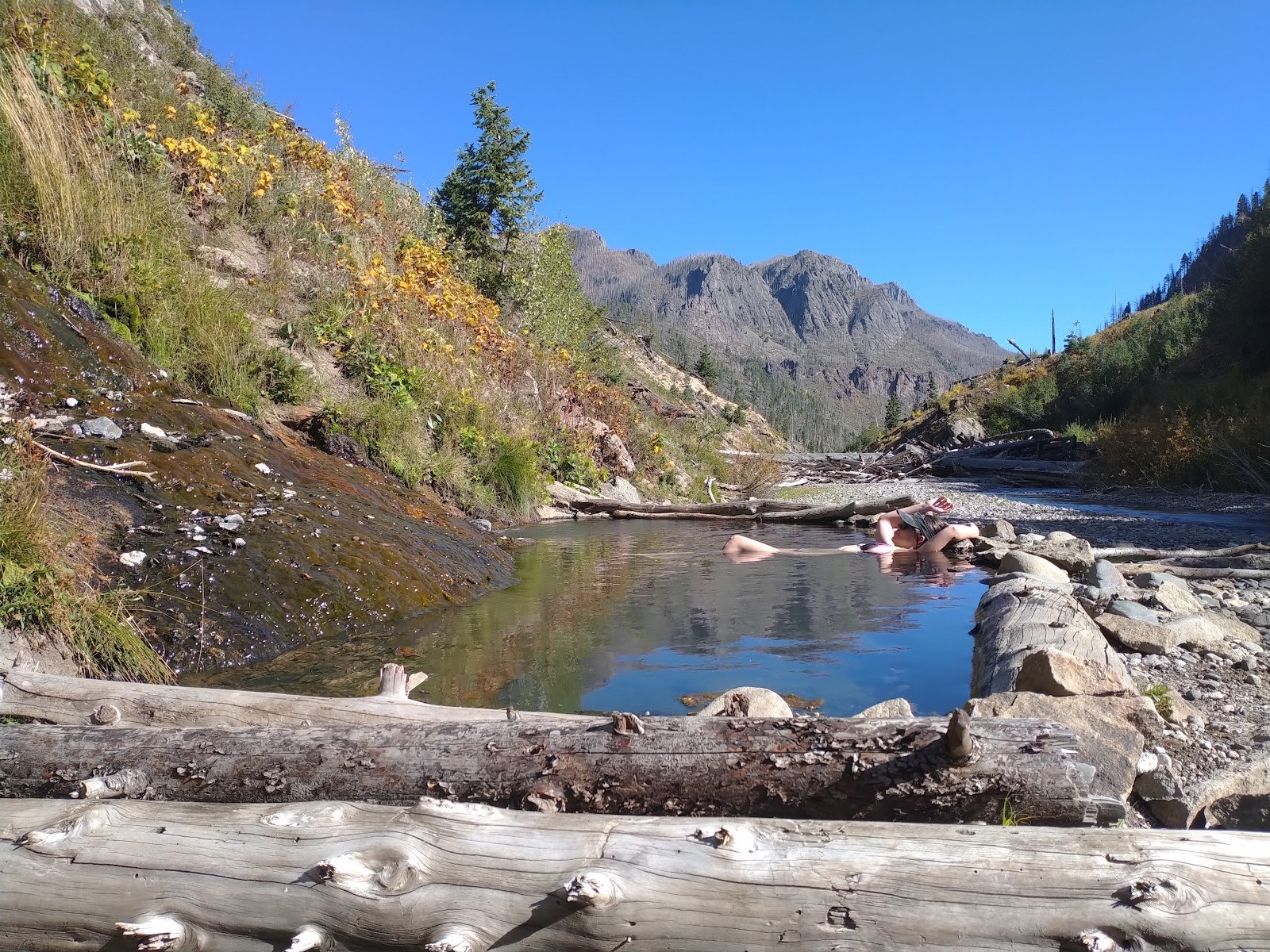 People soaking in a natural hot spring pool at Rainbow Hot Springs surrounded by mountains near Pagosa Springs, Colorado, USA