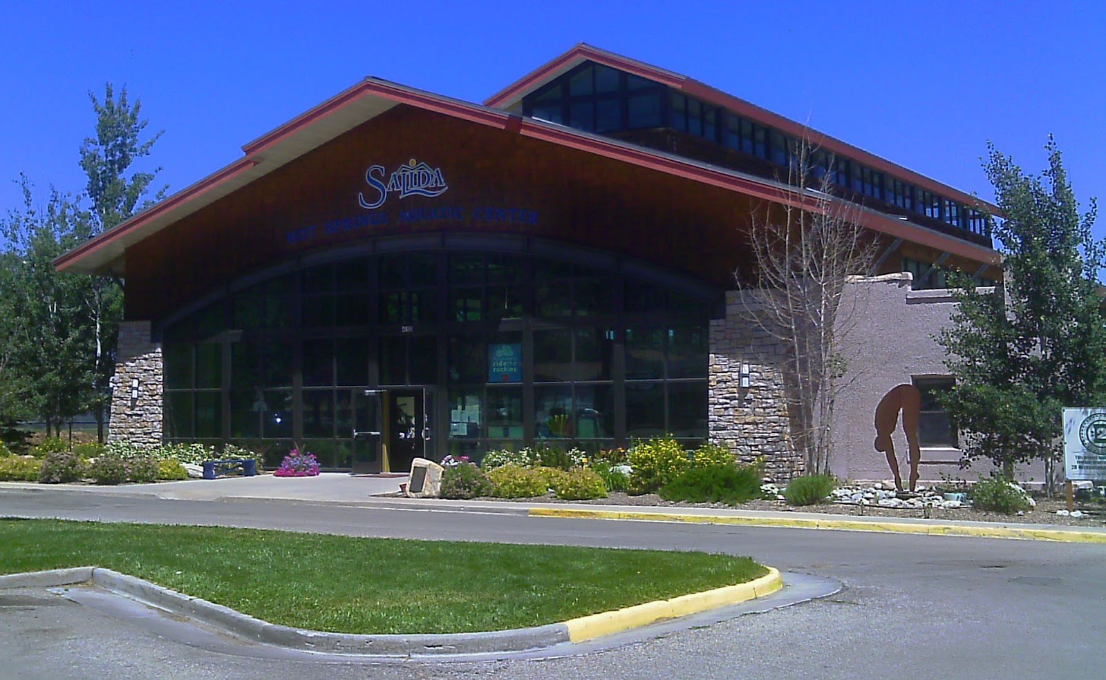 Exterior front view of Salida Hot Springs Aquatic Center building in Salida, Colorado under a clear blue sky.