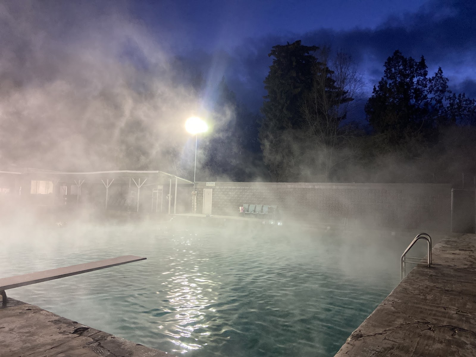 Nighttime view of Banbury Hot Springs outdoor pool with steam rising under a dark sky in Buhl, Idaho, United States