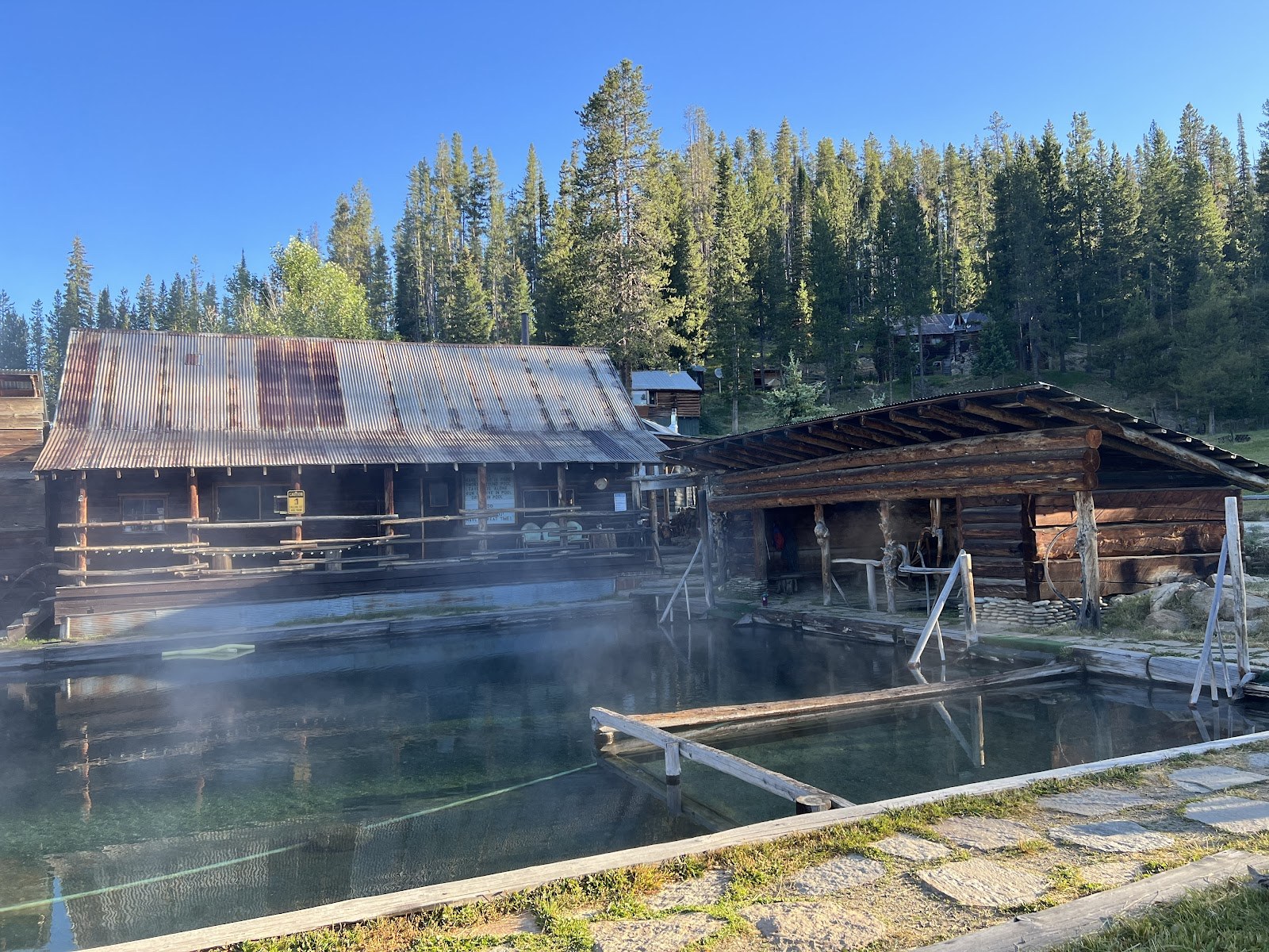 Outdoor hot spring pool with wooden buildings and steam rising at Burgdorf Hot Springs near McCall, Idaho, United States.