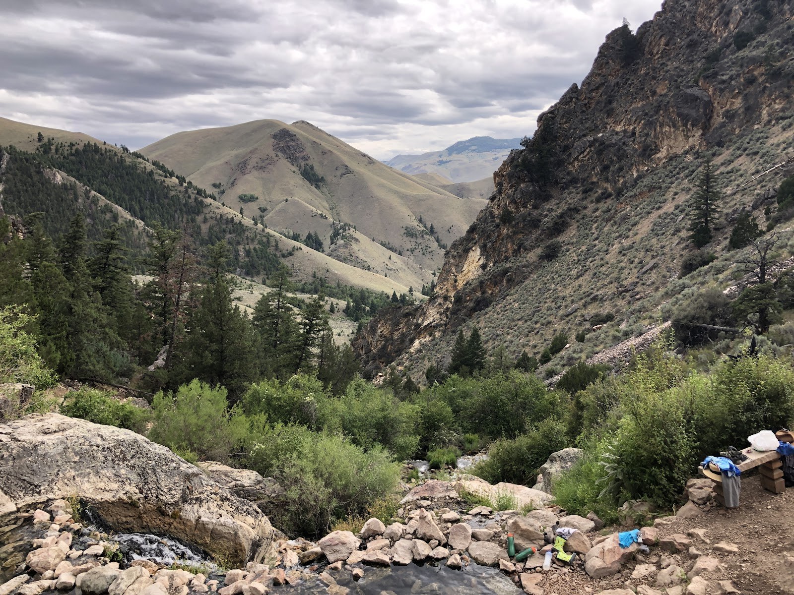 Scenic view of a natural hot spring pool at Goldbug Hot Springs surrounded by pine trees and mountainous landscape near Salmon, Idaho.
