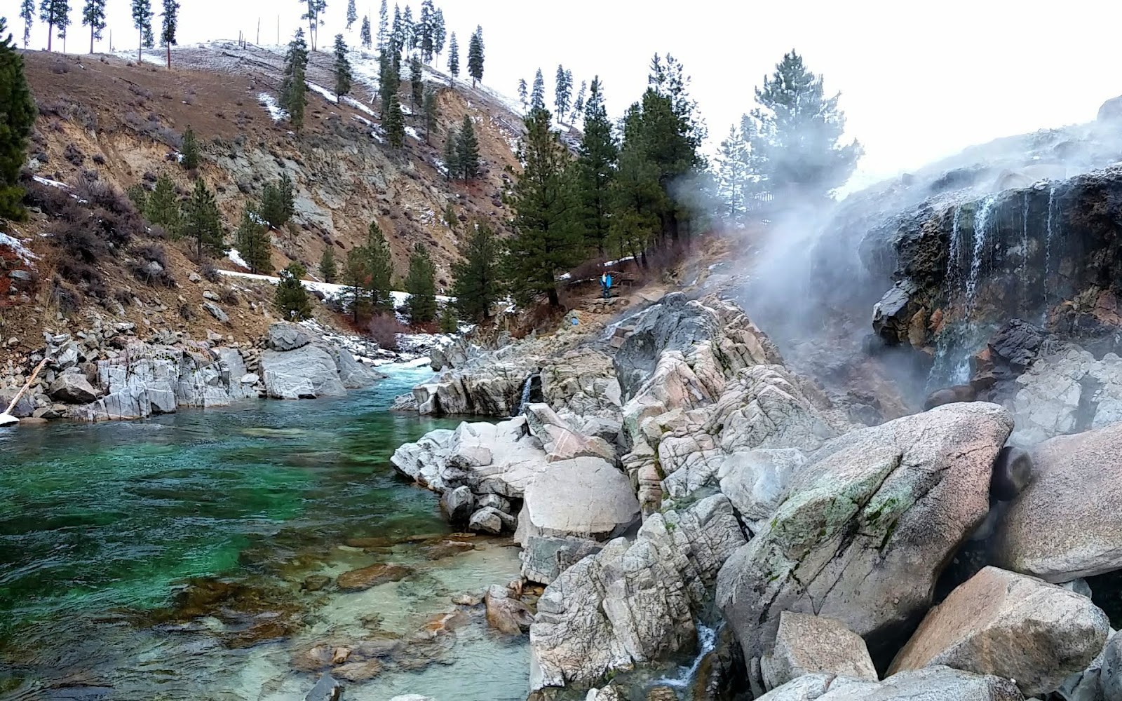 Scenic view of Mile 16 Hot Springs by a clear river with rocky banks and steaming hot water near Cascade, Idaho, USA.