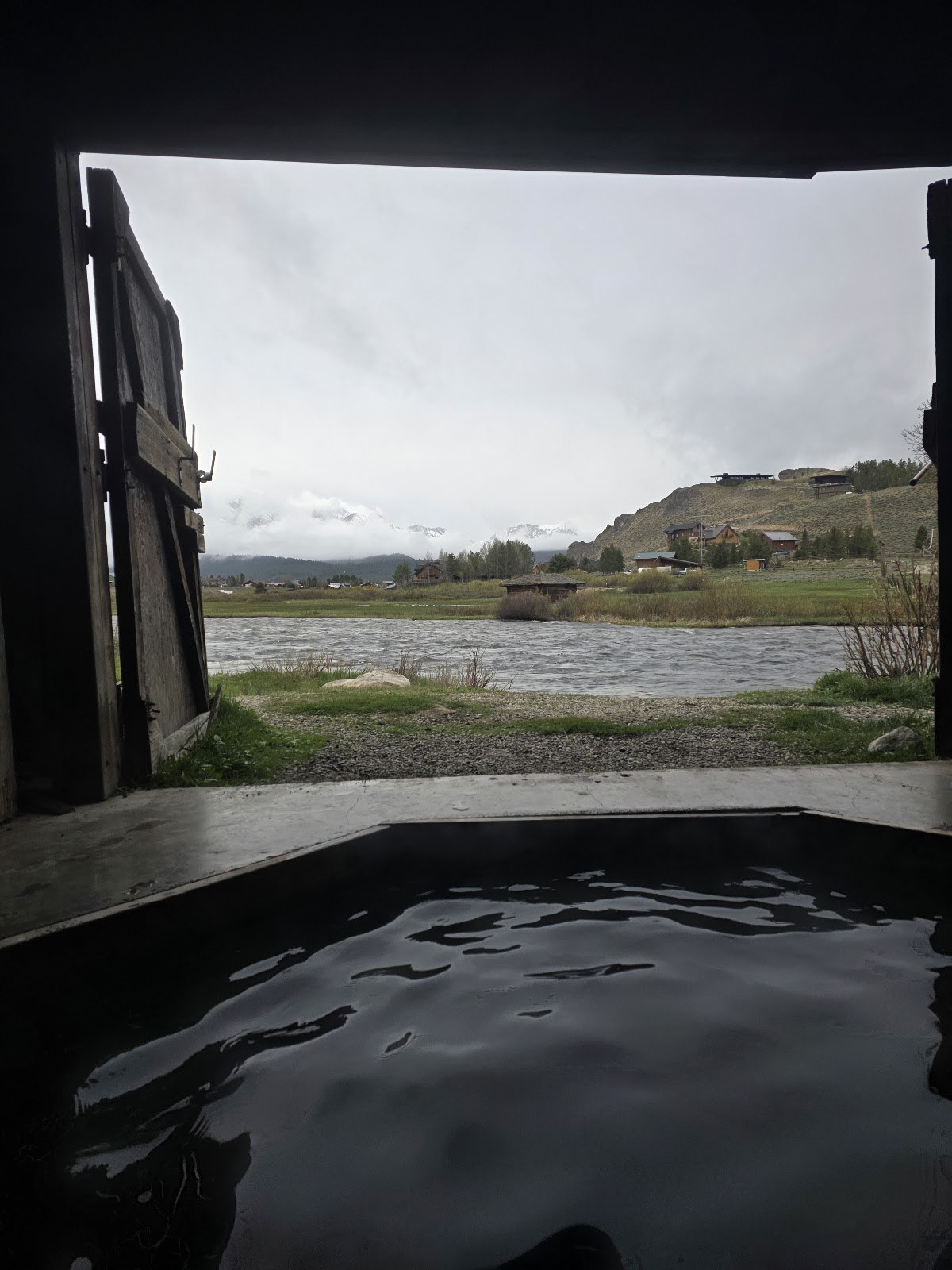 Steaming indoor hot spring pool overlooking the river and distant mountains at Mountain Village Resort Hot Springs near Stanley, Idaho