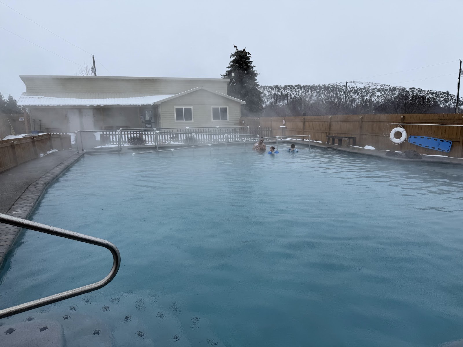 Steaming outdoor hot spring pool at Mundo Hot Springs with people enjoying the warm water on a chilly day near Cambridge, Idaho.