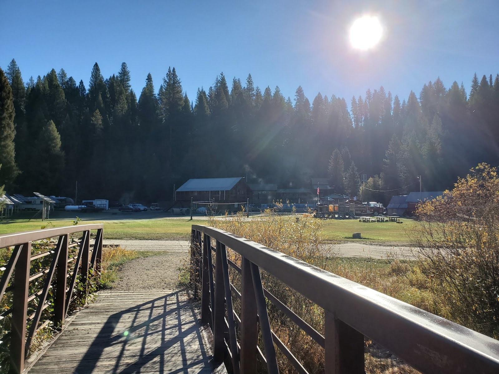 View from the wooden bridge over a small stream looking towards Silver Creek Plunge area with forested hills near Crouch, Idaho.