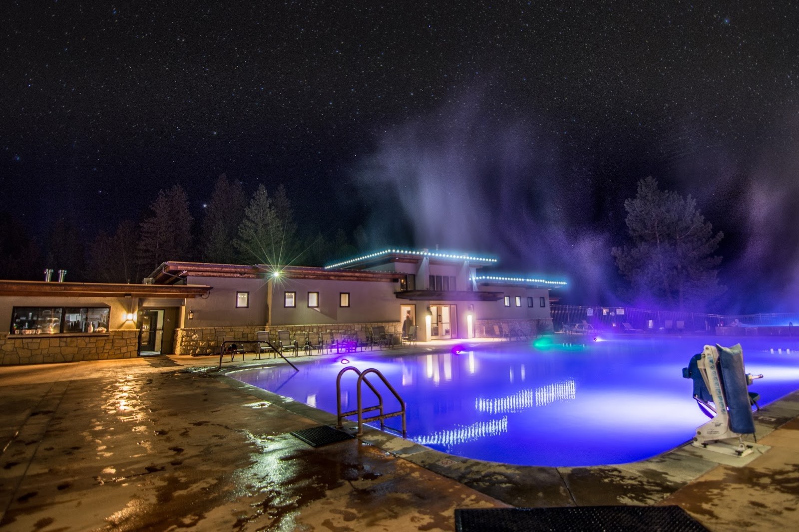 Night view of outdoor pool with steam rising, illuminated by colorful lights at The Springs, Idaho City, Idaho, United States.