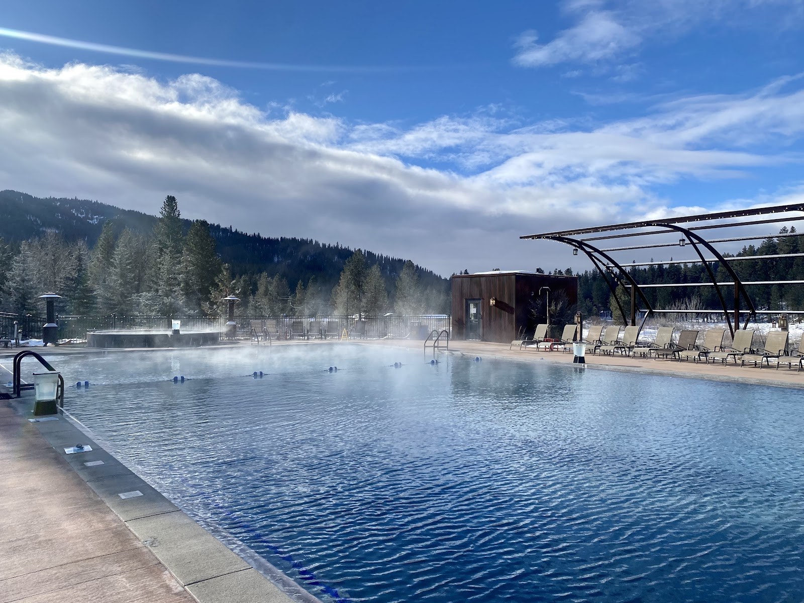 Steam gently rising from a large outdoor hot spring pool with mountainous forest backdrop at The Springs, Idaho City, Idaho.