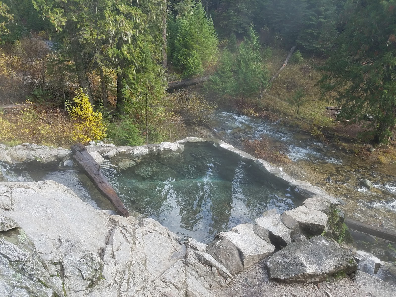 Stone-bordered hot spring pool beside a flowing river at Weir Creek Hot Springs near Kooskia, Idaho in the United States.