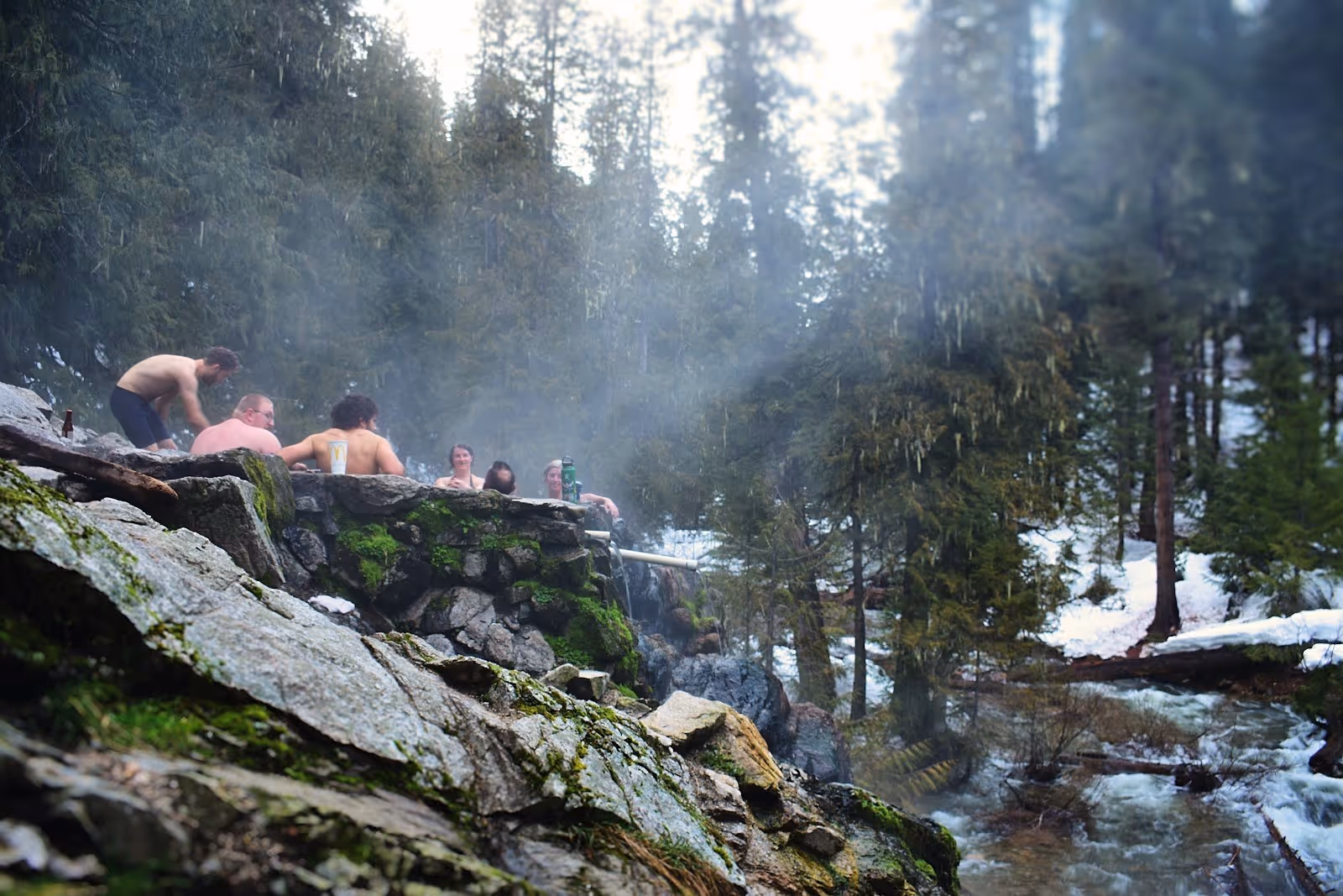 Group of people relaxing in a steaming stone hot spring pool at Weir Creek Hot Springs near Kooskia, Idaho, United States.