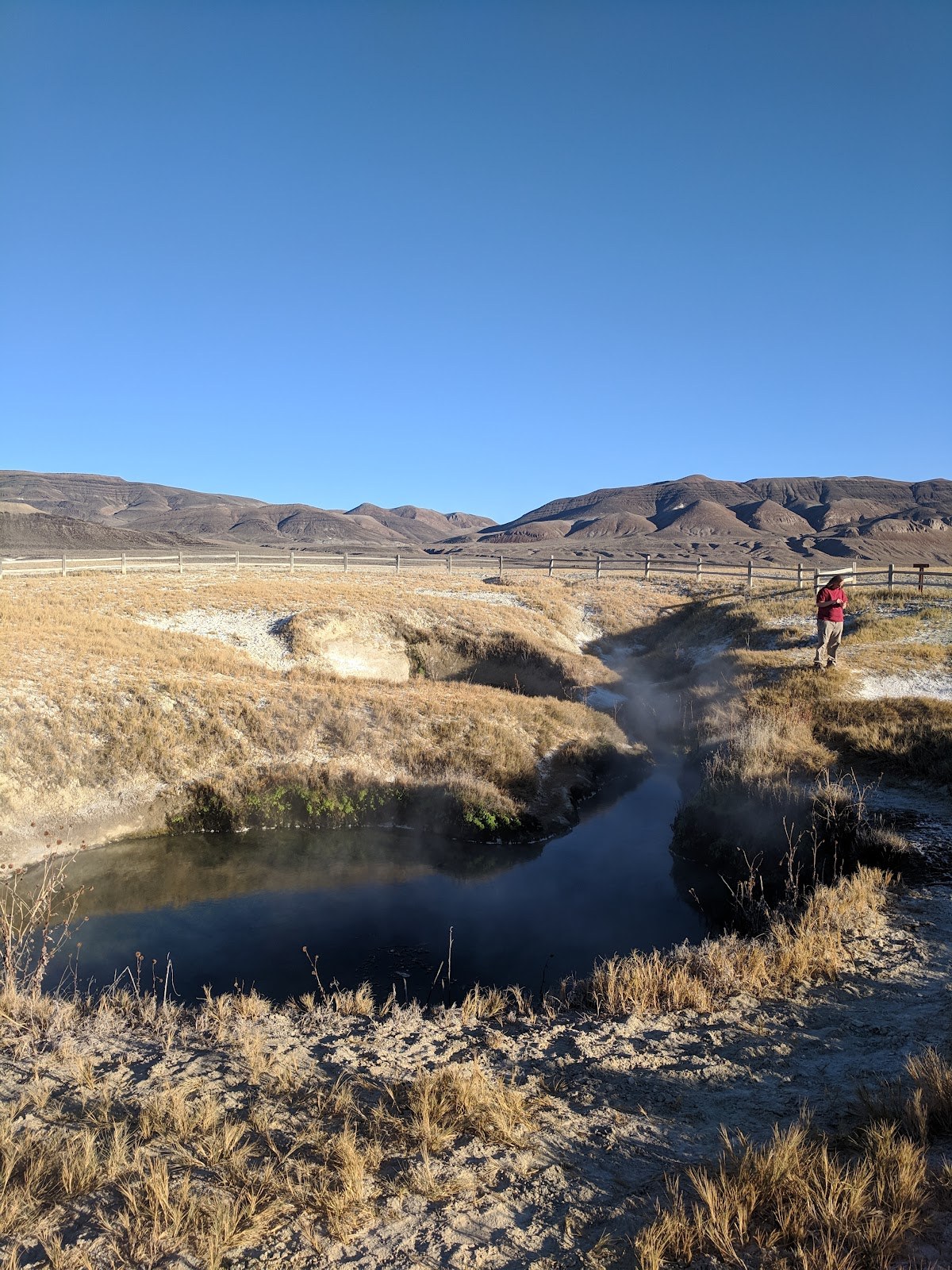 Natural hot spring pool at Double Hot Springs near Gerlach, Nevada, with steam rising under a clear blue sky and distant mountains
