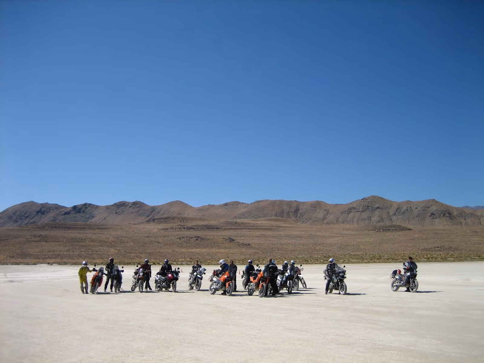Group of motorcyclists gathered on a dry flatland with mountainous terrain under a bright sky near Gerlach, Nevada, United States