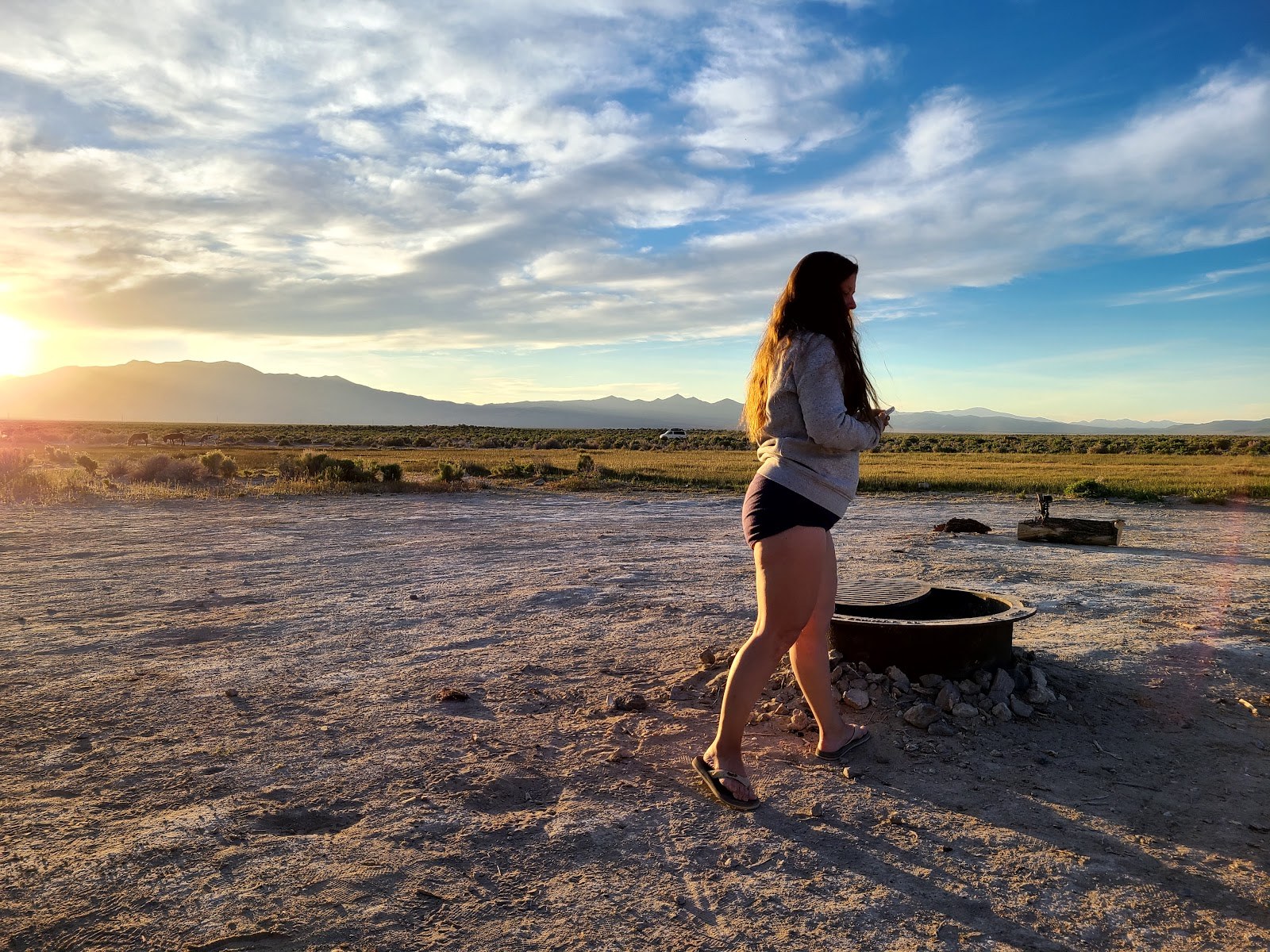 Woman walking near a hot spring pool at Spencer Hot Springs during sunset with mountains visible near Austin, Nevada, United States.