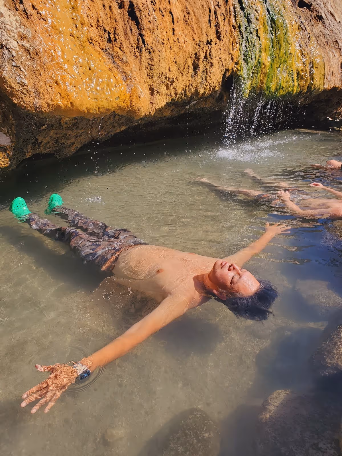 Man floating relaxed in warm mineral water at Buckeye Hot Springs soaking pool near Bridgeport California.