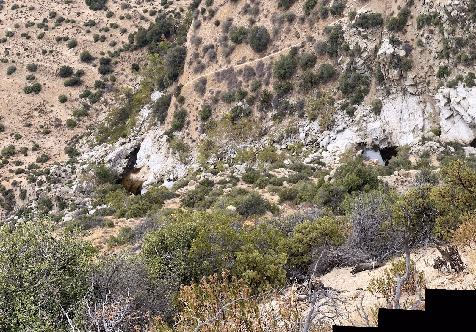 Aerial view of a canyon with rocky slopes and multiple natural water pools visible near Hesperia and Lake Arrowhead in California.