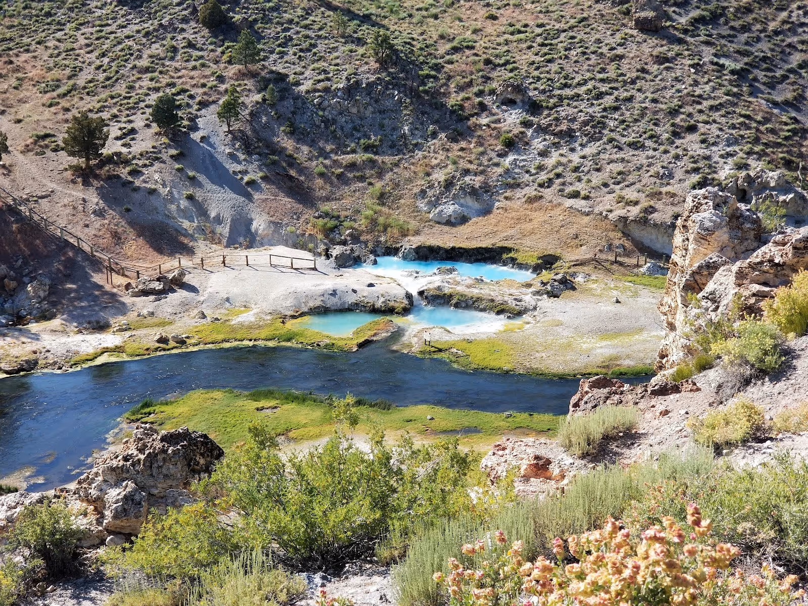 Several clear turquoise hot spring pools beside a flowing river at Hot Creek Geologic Site near Mammoth Lakes california.