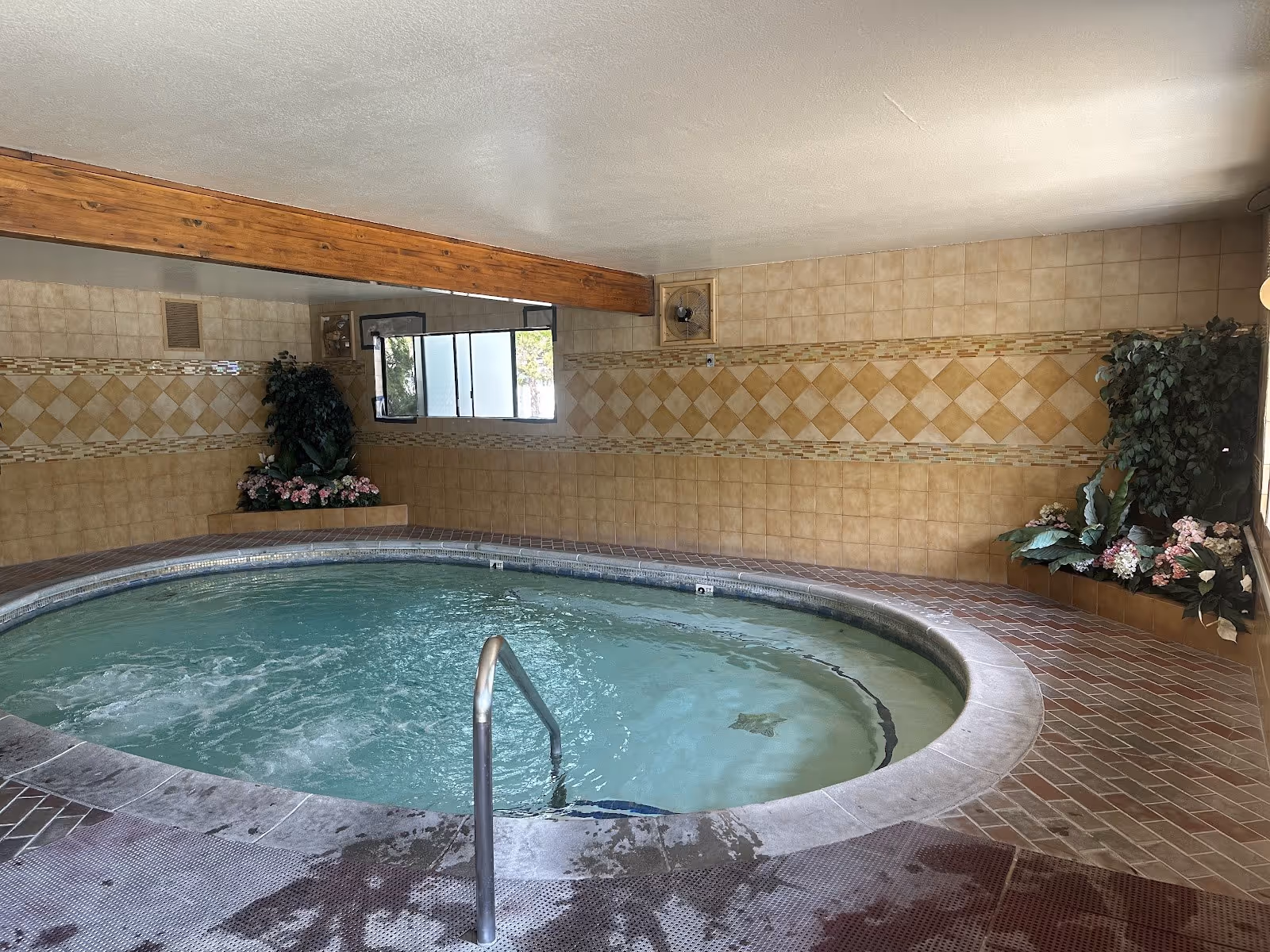 Indoor circular hot spring pool with bubbling water, tiled walls, and decorative plants inside Roman Spa Hot Springs Resort in Calistoga Ca.