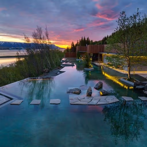 Forest Lagoon outdoor spa pool at sunset with stepping stones and wooden structures near Akureyri Iceland.