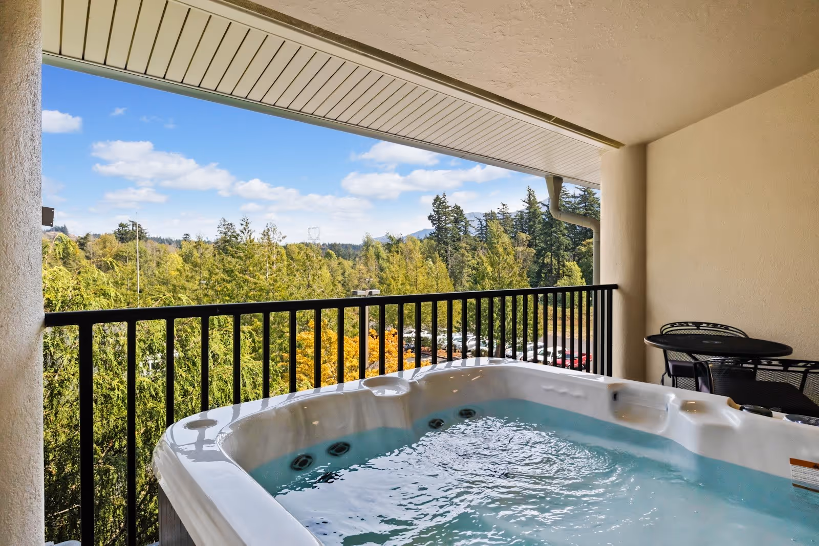 Outdoor balcony hot tub with bubbling water overlooking green forest and distant hills at Bonneville Hot Springs Resort in North Bonneville.