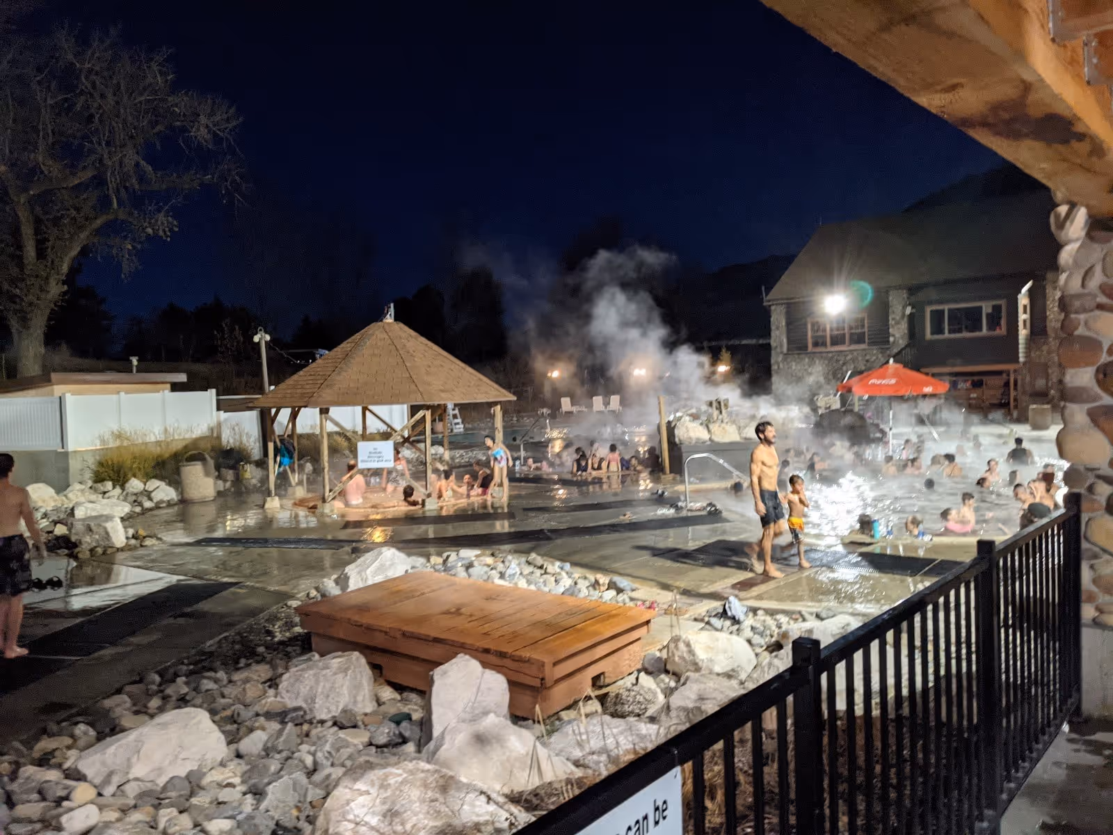 Nighttime view of Roosevelt Hot Springs showing multiple steaming soaking pools surrounded by rocks and structures near Milford Utah.
