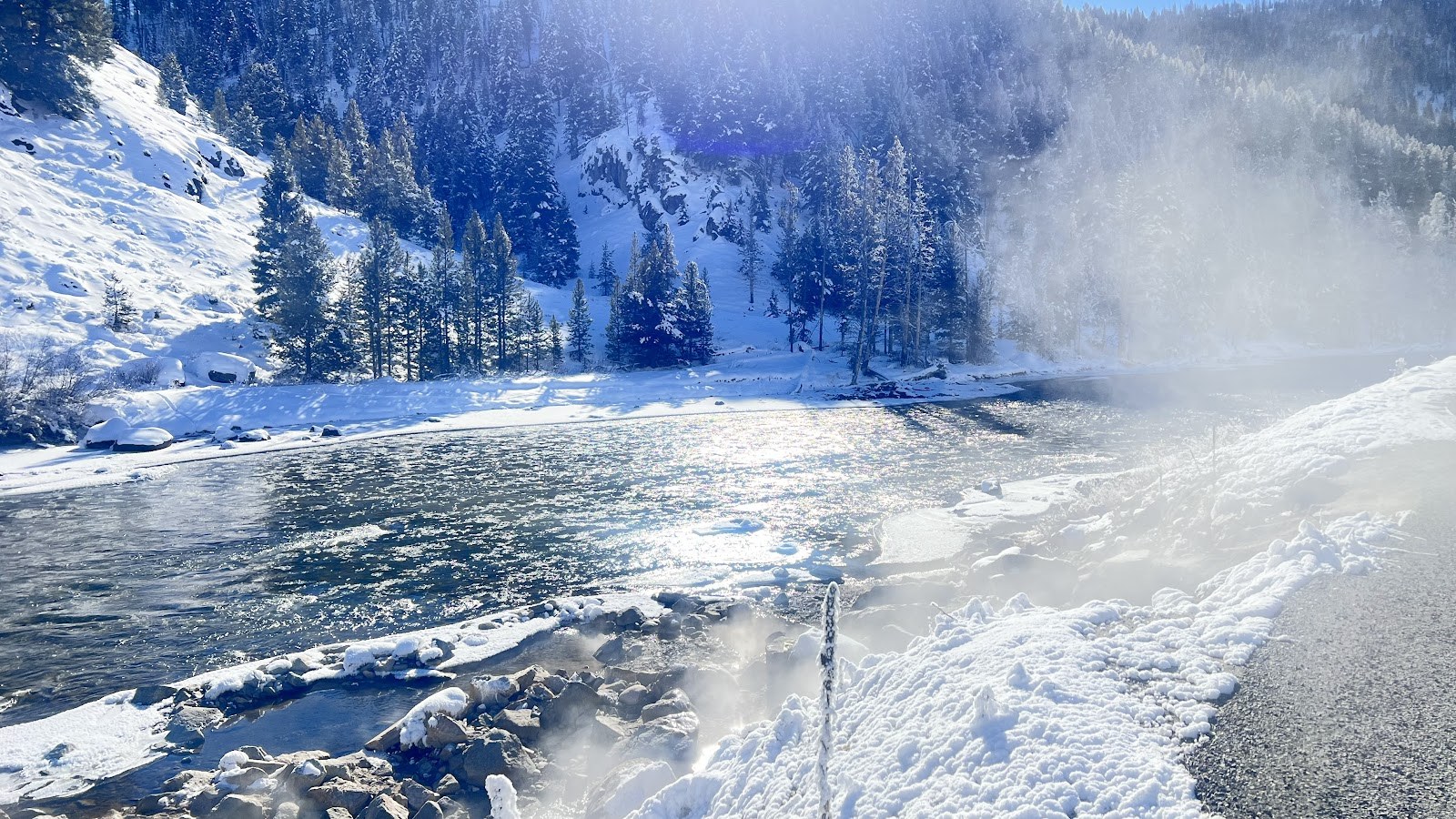 Boat Box Hot Spring in Stanley, Idaho, showing a steamy pool by the river surrounded by snow-covered trees in winter