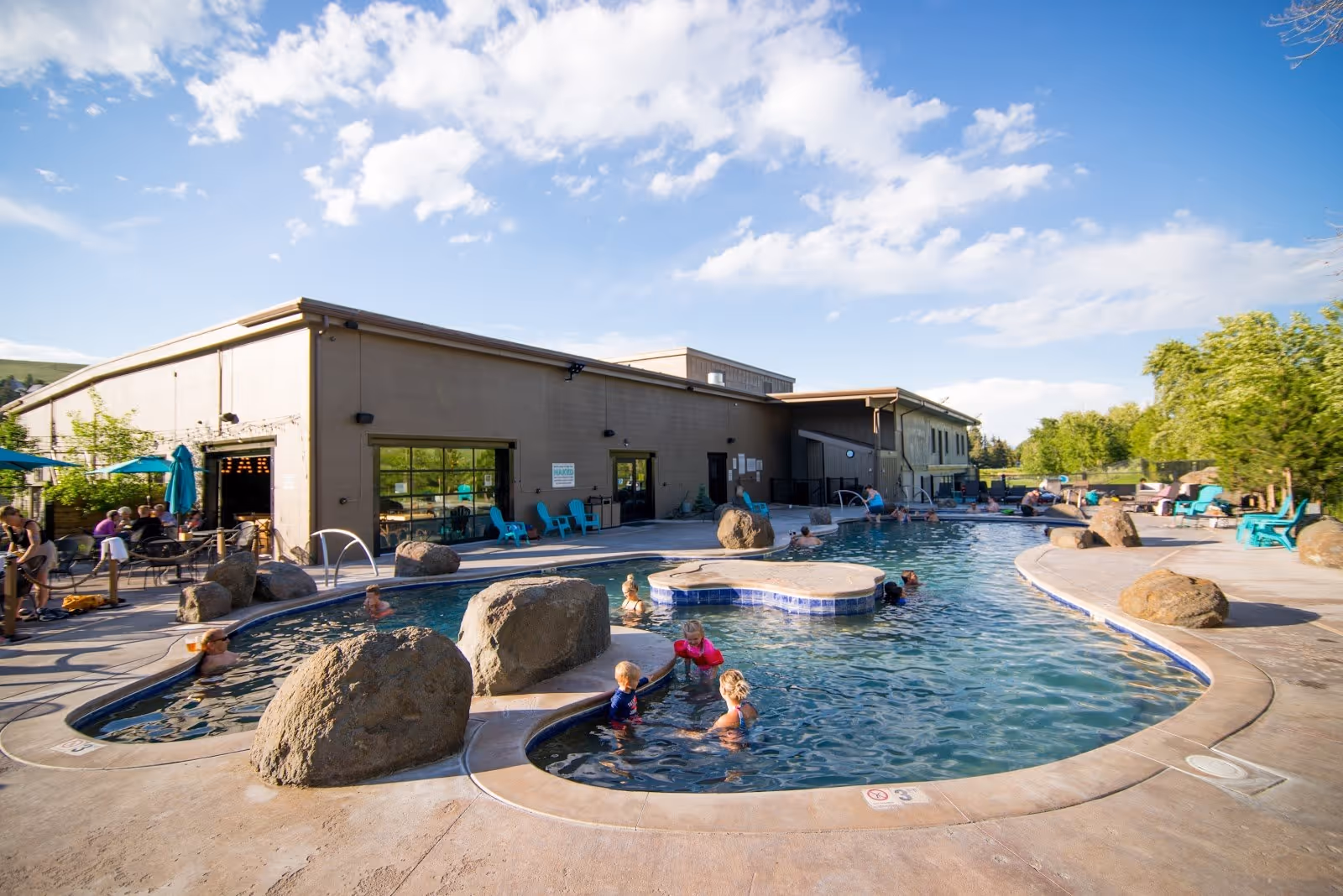 Outdoor pool area at Broadwater Hot Springs with people enjoying the warm water near Helena Montana on a sunny day.