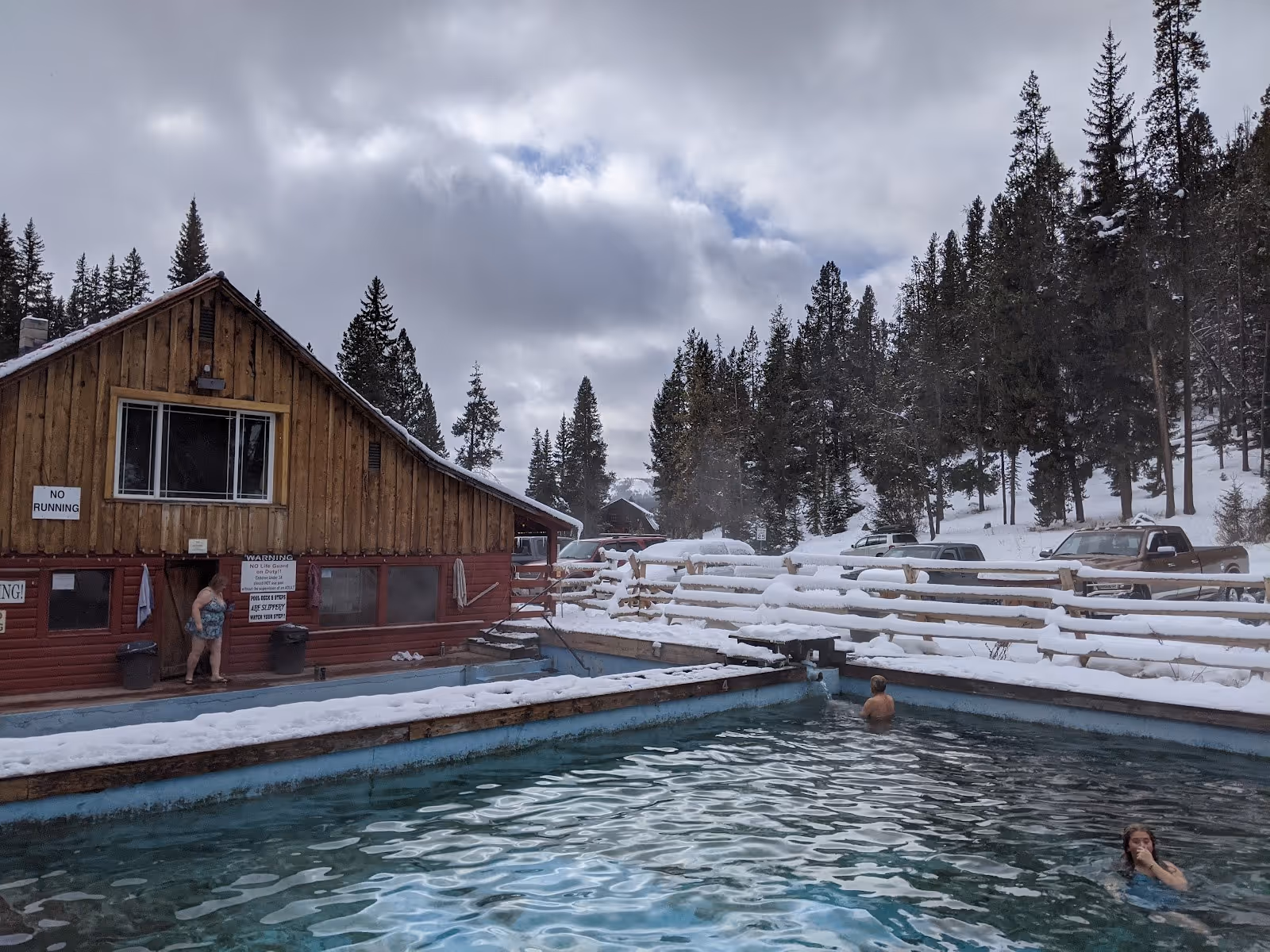 Outdoor soaking pool with steaming water at Elkhorn Hot Springs in Polaris, Montana, surrounded by snow and pine trees.
