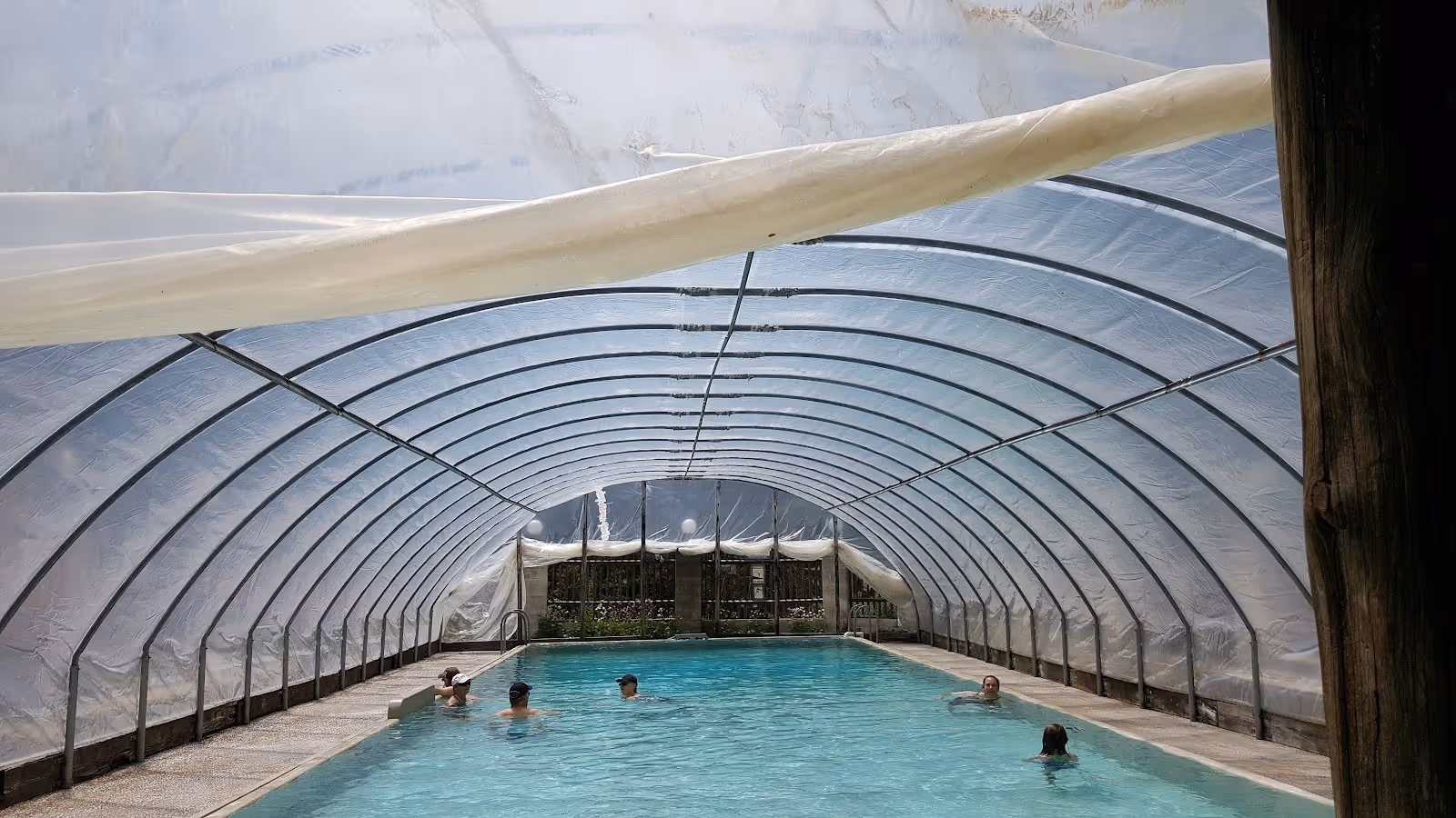 Children enjoying the covered mineral pool with a metal arch structure at Lost Trail Hot Springs located in Montana.