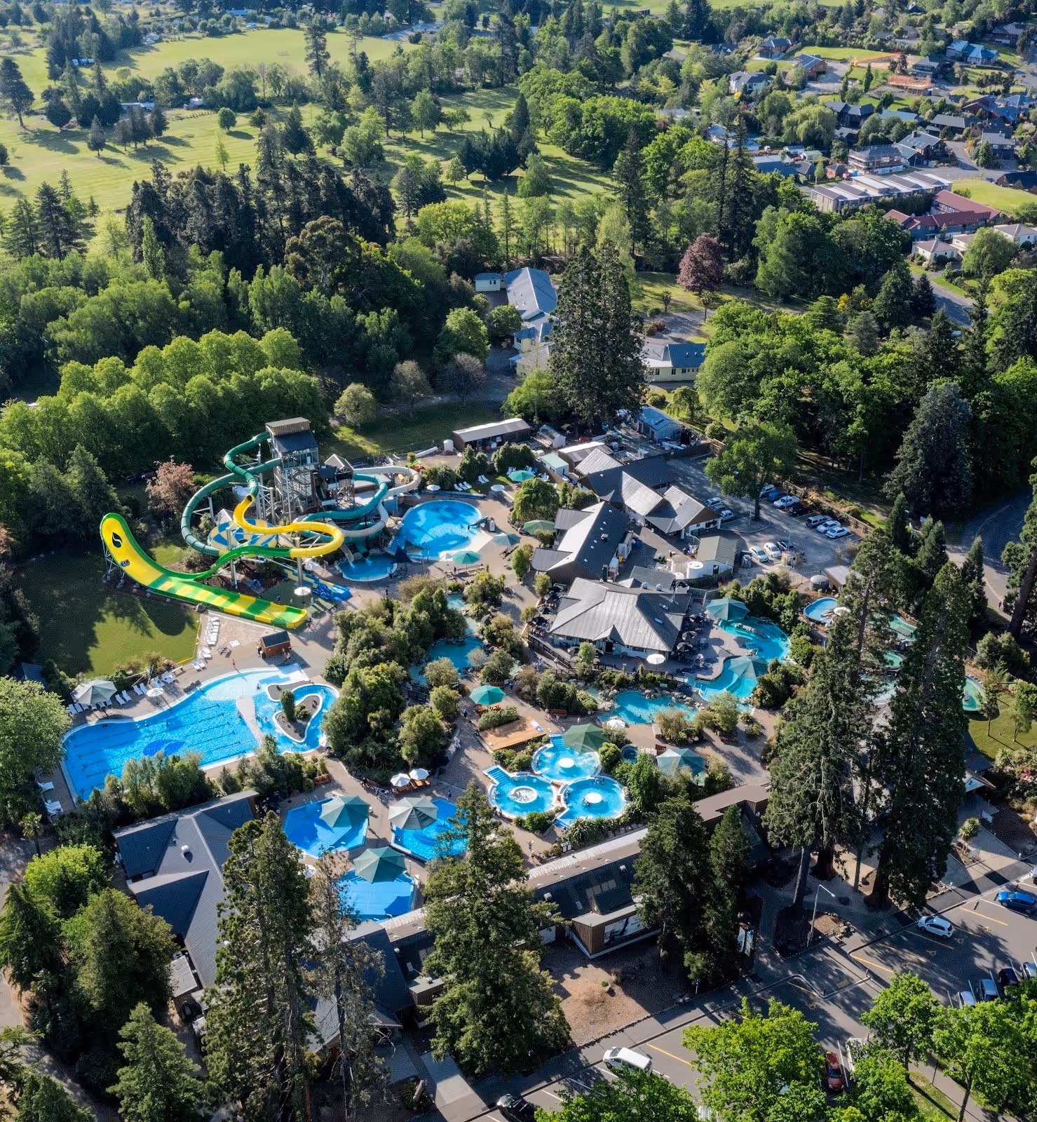 Aerial view of Hanmer Springs Thermal Pools & Spa with multiple pools water slides and surrounding green trees in Hanmer Springs New Zealan.