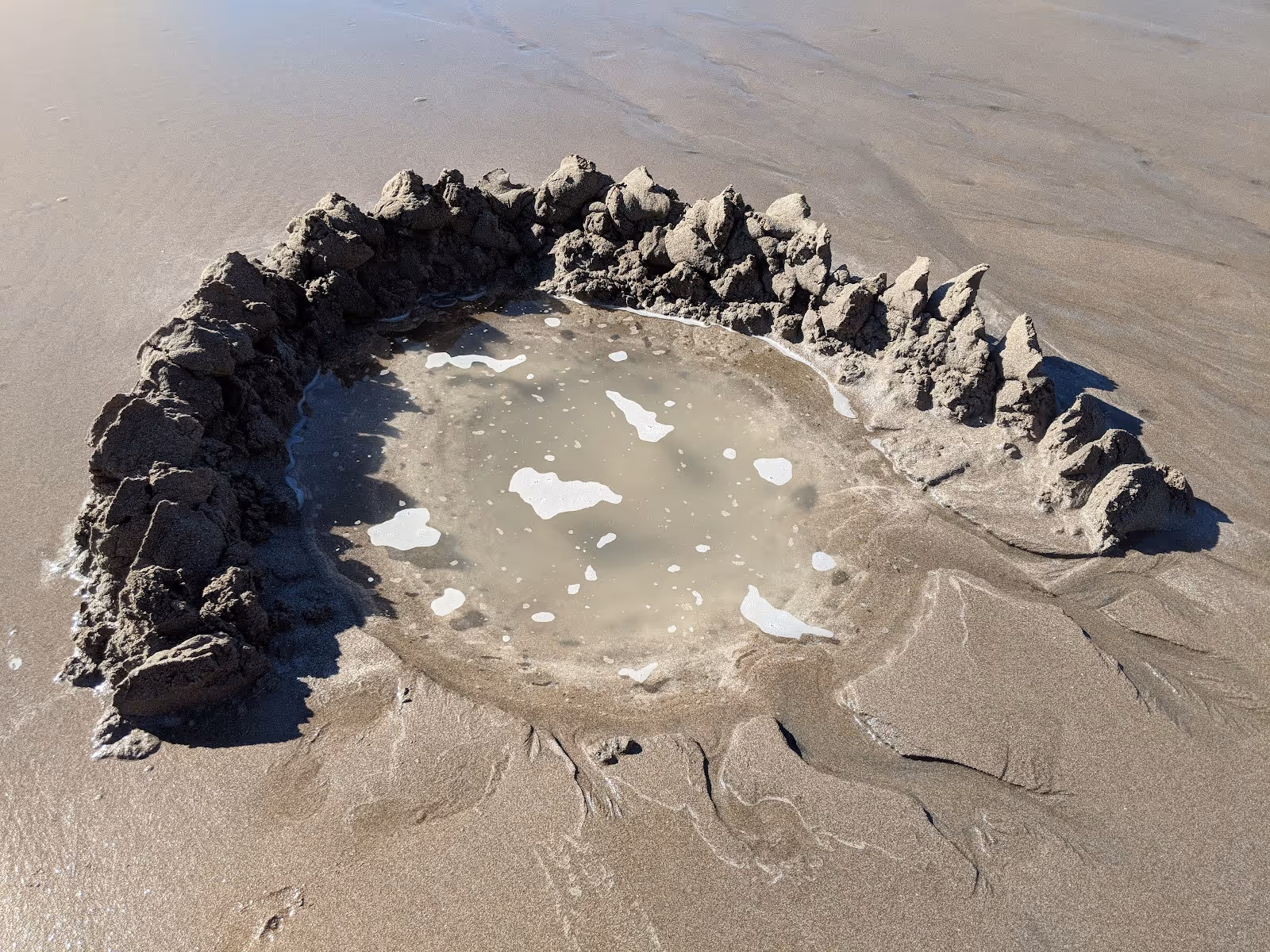 Close view of a hand dug hot water pool filled with warm water on the sand at Hot Water Beach near Whitianga New Zealand.
