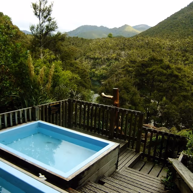 Mangatutu Hot Springs rectangular soaking pool on wooden deck with forested hills near Napier, New Zealand.